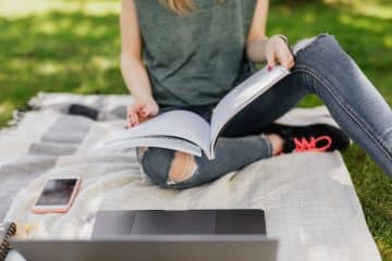 woman reading book on grass